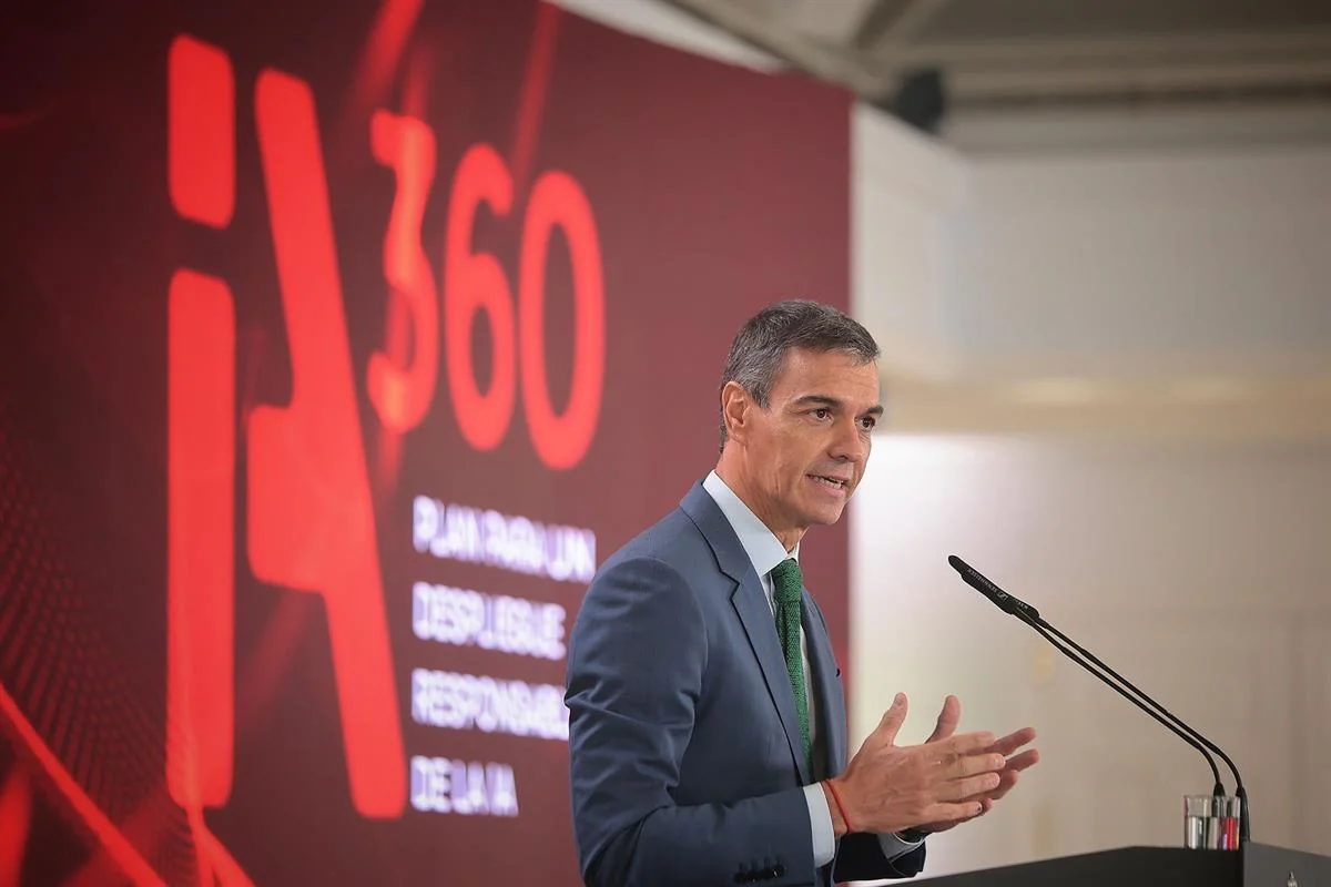 Fotografia de Pedro Sánchez, de vestit blau i corbata verda, parlant i gesticulant davant de dos micròfons de faristol. Al darrere, un plafó vermell amb el logotip «iA360» i el lema «Plan para un despliegue responsable de la IA».